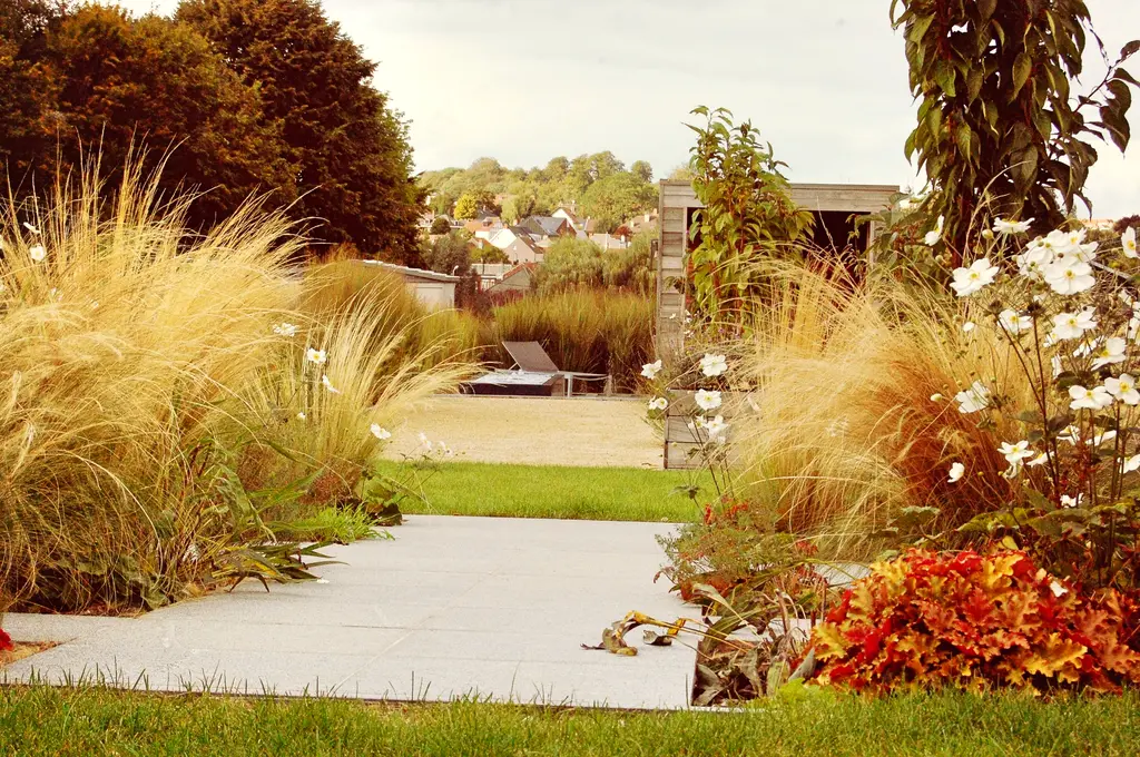 Tegelpad langs plantvakken met siergrassen, gazon en tuinkamer achteraan — De kracht van beplanting, Itterbeek