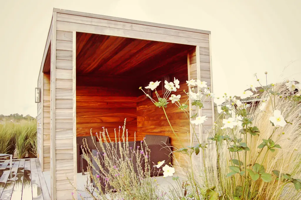 Open houten tuinkamer achter wit bloeiende vaste planten en siergrassen — De kracht van beplanting, Itterbeek