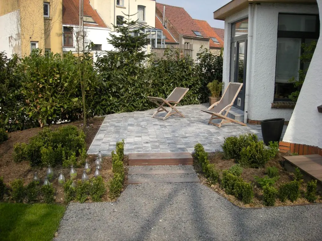 Klein terras van kasseien met twee strandstoelen naast de witte woning, jonge heesters — Gezellige stadstuin, Ukkel