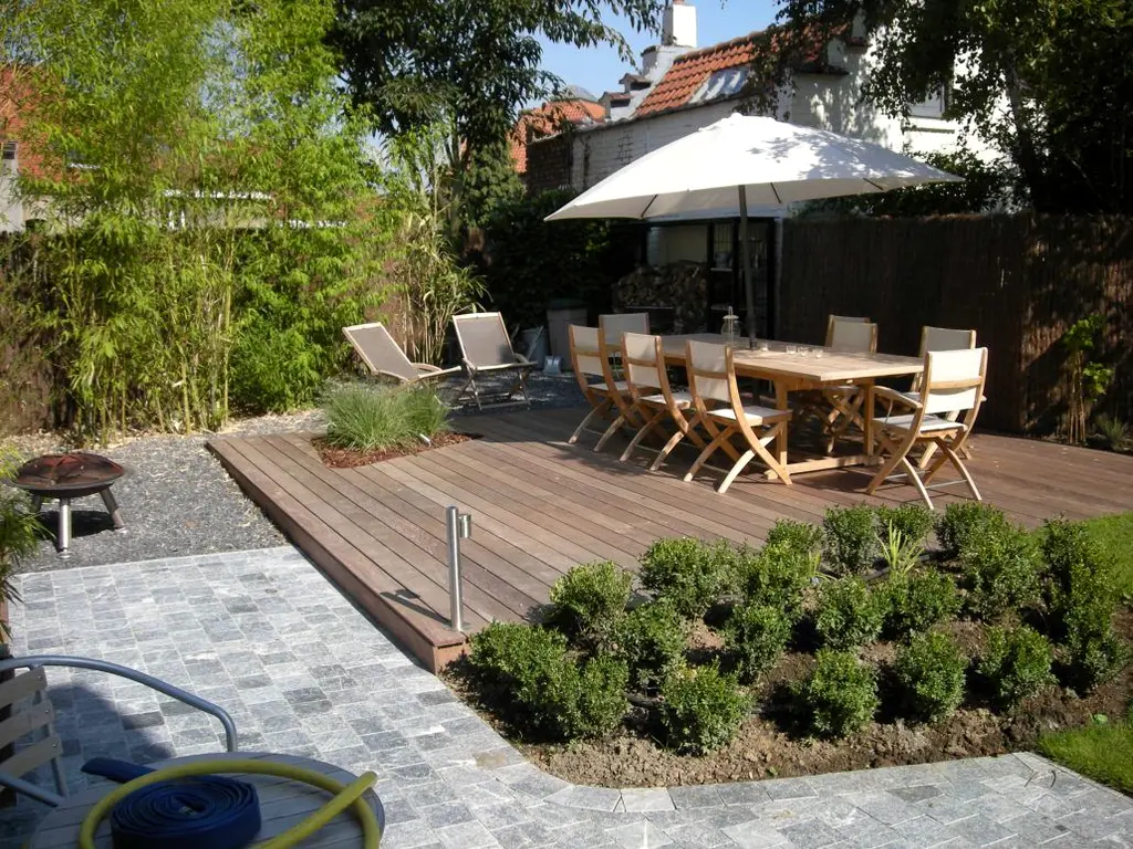 Houten terras met tuintafel onder witte parasol, ligstoelen en pad van kasseien — Gezellige stadstuin, Ukkel