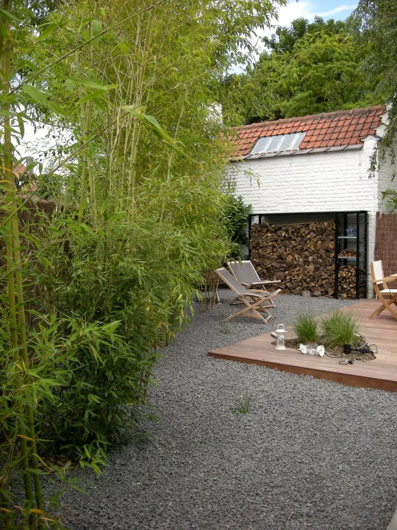 Grindpad langs bamboe naar houten vlonder met strandstoelen en wit bijgebouw — Gezellige stadstuin, Ukkel