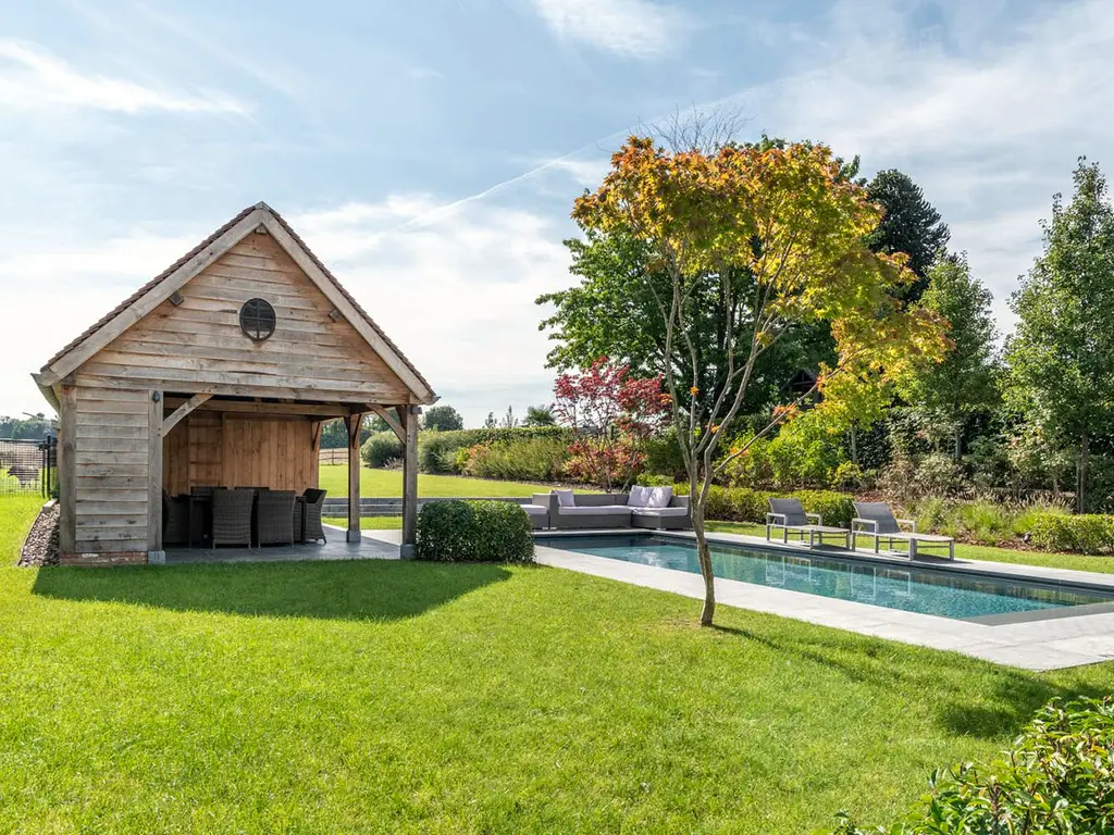 Houten poolhouse met pannendak en overdekte zithoek naast het zwembad — Klassieke tuin met zwembad, Roosdaal