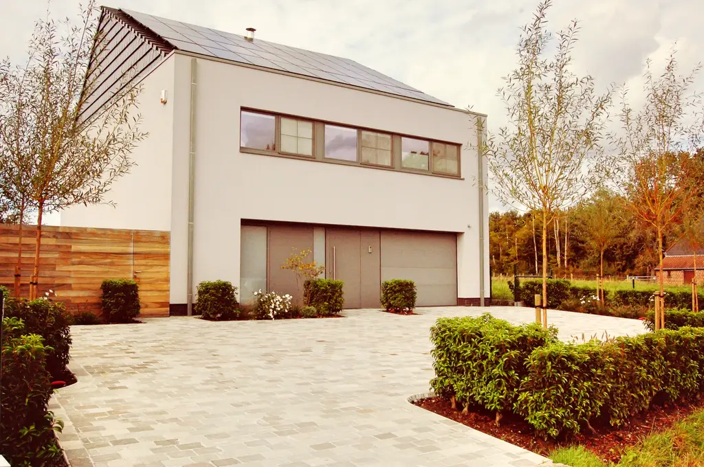 Oprit van lichte kasseien met haagblokken en jonge bomen voor de moderne woning — Open en toch gezellig