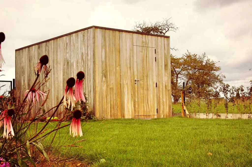 Houten tuinberging in het gazon met roze bloeiende vaste planten vooraan — Open en toch gezellig