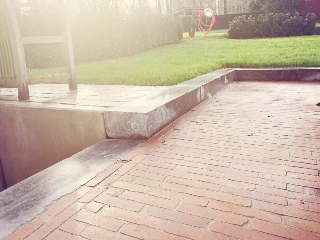 Stenen trede tussen klinkers en gazon, met een houten ladder — Romantische tuin met zwembad, Asse