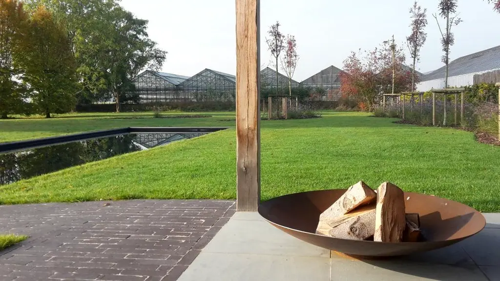 Vuurschaal op klinkerterras, gazon met waterspiegel en serres in de verte — Sobere kwaliteit, Wolvertem