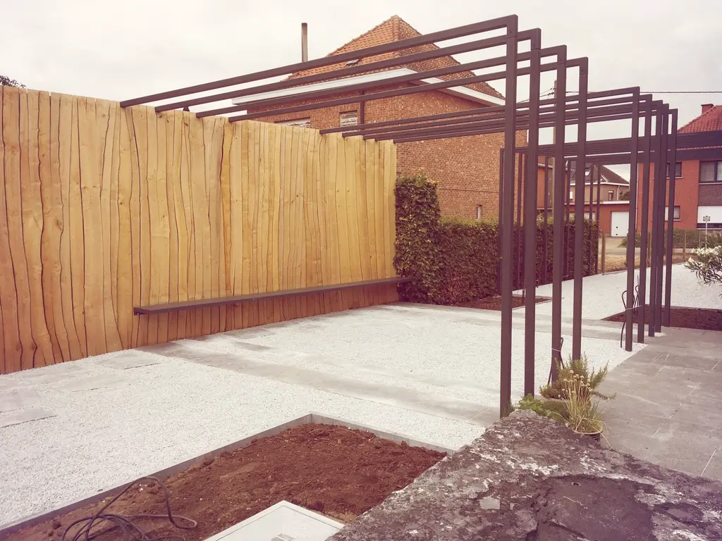 Donkere stalen pergola over lichte verharding naast houten wand met zitbank — Stijlvolle leeftuin, Hofstade